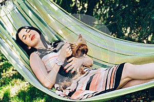 Girl sleep in hammock on nature with a dog in her arms