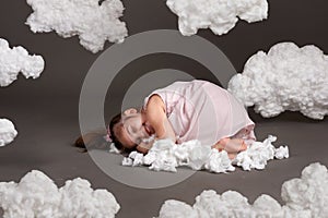 Girl sleeping on a cloud, shot in the studio on a gray background