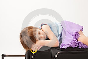 Girl sleeping on a road suitcase on white background