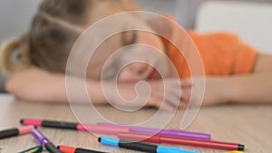 Girl sleeping on table in kindergarten, exhausted after tiring art lesson, close