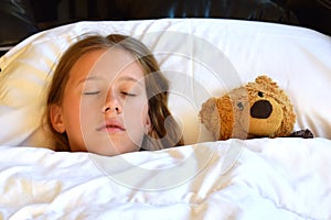 Girl sleeping with a teddy bear. The child is sleeping sweetly with his favorite toy