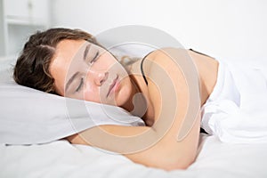 Girl sleeping on white bedlinen in bed at home