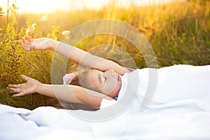 Girl sleeps on bed in grass, Sweet stretches and yawns sleepily, good morning in fresh air. Eco-friendly, healthy sleep, benefits photo