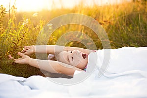 Girl sleeps on bed in grass, Sweet stretches and yawns sleepily, good morning in fresh air. Eco-friendly, healthy sleep, benefits photo