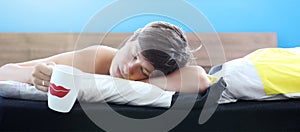 Girl sleeps in bed on pillow with a cup of weekend morning tea or coffee, wide banner format