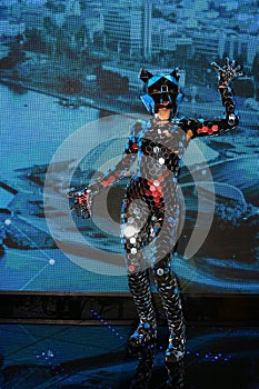 A girl with a slender figure in a fantastic mirror suit with a mask of mirrors performing in the arena