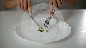 Girl slicing cucumber, obsessed with undereating, fear of overweight, anorexia photo