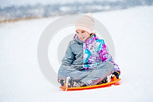 Girl sliding down the hill on saucer sled
