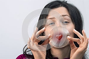 Girl with slitted eyes holding a glass with a red heart symbol photo