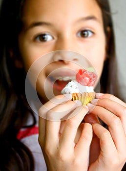 A girl with a small cupcake covered in frosting.