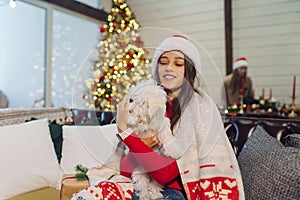 Girl with a small dog in her arms sits on the couch on new year& x27;s eve