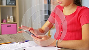 Girl with smartphone distracting from homework