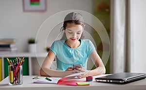 Girl with smartphone distracting from homework photo