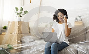 Girl with smartphone and laptop, sits on couch covered oilcloth photo