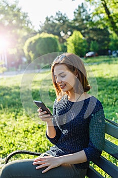 Girl with a smartphone sitting in a park