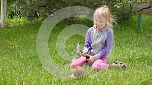 Girl smashes coconut with a heavy iron hammer sitting on the grass 01