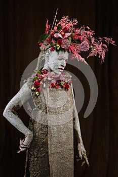 A girl smeared with clay in a cemented dress. The model has a headdress made of flowers