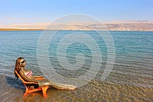 Girl smeared with therapeutic mud sunbathes, Dead Sea