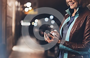 Girl smile pointing finger on screen smart phone on background illumination color light in night atmospheric city, hipster using