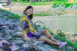 The girl smile and sit on the rock front of Dam bridge