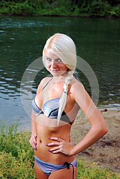 Girl smiles in bikini in a meadow near river