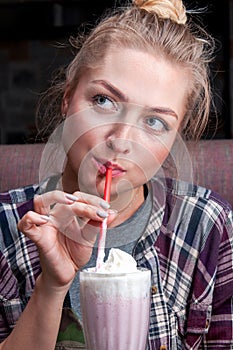 The girl smiles and drinks a milkshake.