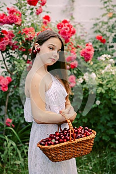 Girl smiles and holds cherries near her ears as if they were earrings