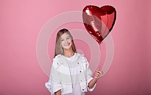 A girl smiles and holds a heart shaped balloon