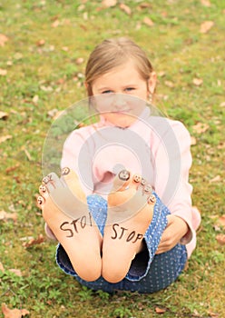 Girl with smileys on toes and sign STOP on soles