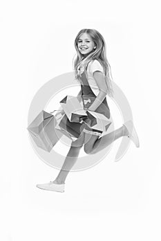 Girl on smiling face carries bunches of shopping bags, isolated on white background. Kid girl with long hair fond of