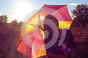 Girl smiling hiding under colorful umbrella