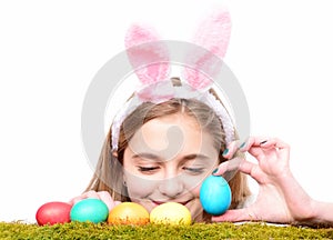 Girl smiling with painted eggs on green grass, spring