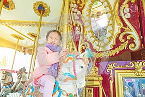 Girl smiling while riding a horse in merry-go-round