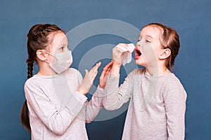 Girl sneezes hiding behind a handkerchief. The second girl protects herself from her with a mask and hands. Infecting children