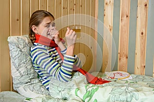 Girl sneezes while sitting in bed with a cup of hot tea photo