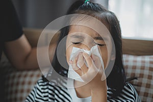 A girl is sniffling and wiping her nose with a tissue photo