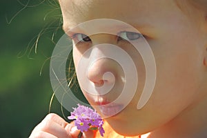 Girl sniffs a lilac bunch of flowers puffy lips serious look