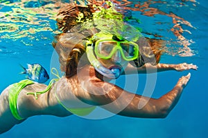 Girl in snorkeling mask dive underwater with coral reef fishes