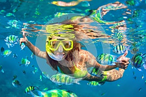 Girl in snorkeling mask dive underwater with coral reef fishes photo