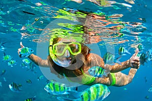 Girl in snorkeling mask dive underwater with coral reef fishes photo