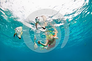 Girl in snorkeling mask dive underwater with tropical fishes