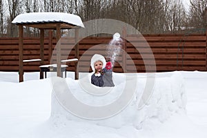 Girl in snow fortress playing snowballs