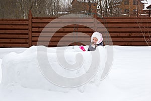 Girl in snow fortress playing snowballs