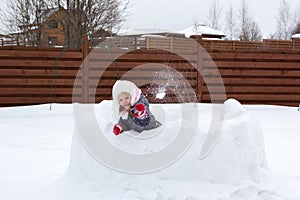 Girl in snow fortress playing snowballs