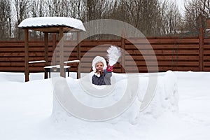 Girl in snow fortress playing snowballs