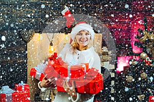 Girl in snow. Young woman with christmas present boxes in front of christmas tree. Cheerful young woman wearing