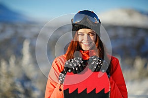 Girl with snowboard on top of the mountain