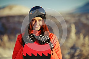 Girl with snowboard on top of the mountain