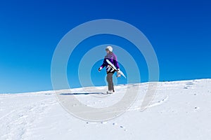 Girl with snowboard at the top of a mountain