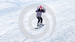 Girl snowboarder descends from the mountains in the snow on a snowboard